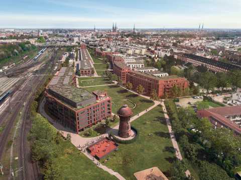 Luftaufnahme eines modernen Stadtteils mit roten Gebäuden und einem Wasserturm.