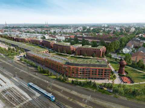 Modernes Wohnviertel mit begrünten Dächern, Bahnstrecke und Wasserturm im Vordergrund.