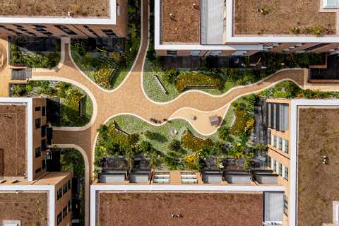 Vogelperspektive auf begrünten Innenhof mit geschwungenen Wegen und Beeten.