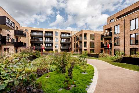 Moderner Innenhof mit begrüntem Garten, umgeben von mehrstöckigen Wohnhäusern.