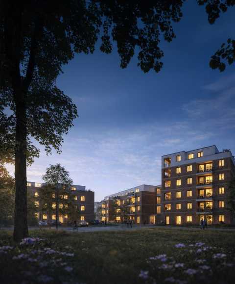 Mehrere Wohngebäude am Abend mit leuchtenden Fenstern und Grünfläche.