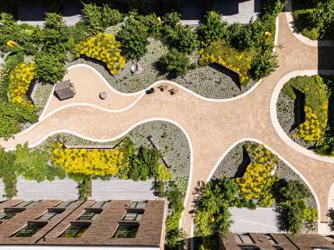 Hofgarten mit geschwungenen Wegen, Beeten und gelben Blumen von oben.