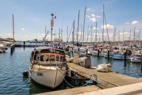 Kleiner Hafen mit Fischerboot im Vordergrund und vielen Segelbooten im Hintergrund.