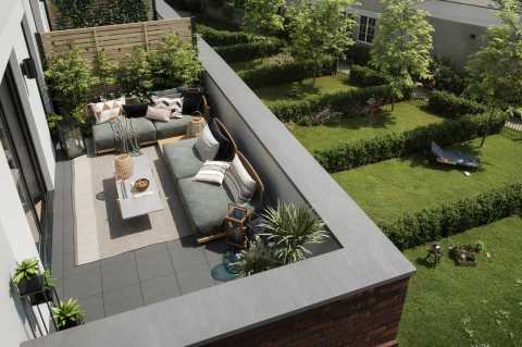 Gemütlicher Balkon mit Sofas, Pflanzen und Blick auf einen grünen Garten.