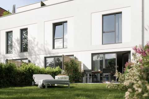 Modernes weißes Reihenhaus mit Garten, Terrasse, Liege und Sitzgruppe.