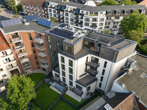 Modernes Mehrfamilienhaus mit Solaranlagen und Balkonen, Vogelperspektive.