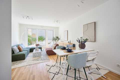 Helles Wohnzimmer mit Essbereich, Sofa, Tisch und großen Fenstern zum Garten.