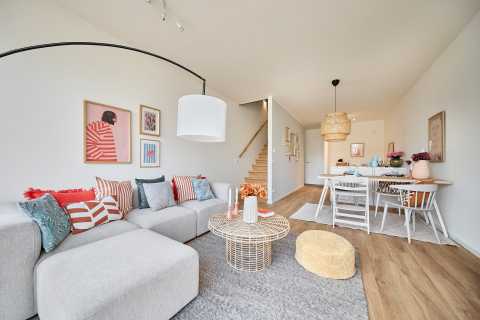 Modernes Wohnzimmer mit Sofa, Esstisch, bunten Kissen und heller Dekoration.