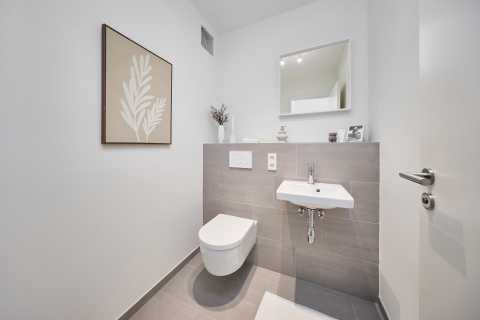 Modernes, helles WC mit Hänge-WC, kleinem Waschbecken und minimalistischem Dekor.