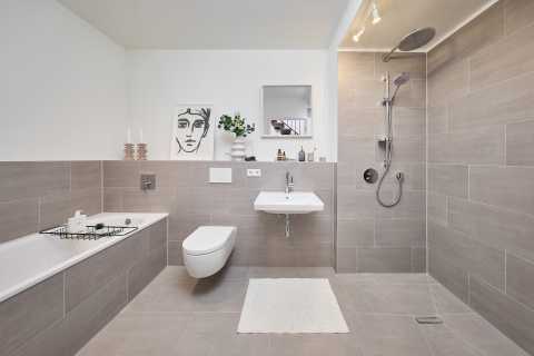 Modernes, helles Badezimmer mit Badewanne, Dusche, WC und Waschbecken.