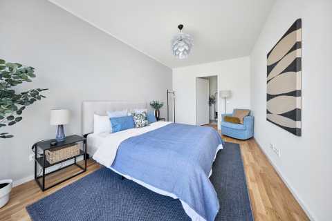 Helles Schlafzimmer mit Doppelbett, blauer Decke, Sessel und moderner Deko.