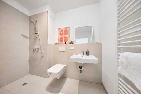 Modernes barrierefreies Bad mit ebenerdiger Dusche, WC und Waschbecken.