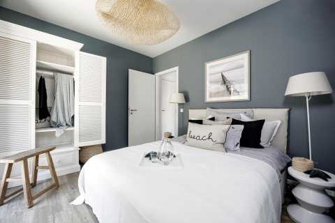 Modernes Schlafzimmer mit grauen Wänden, weißem Bett und offenem Kleiderschrank.