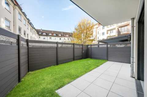 Moderner kleiner Garten mit Rasen, Fliesen und Sichtschutzzaun in der Stadt.