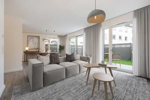 Modernes Wohnzimmer mit grauem Sofa, Couchtischen und großen Fenstern zum Garten.