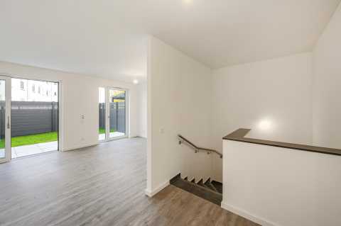 Helles, modernes Wohnzimmer mit großen Fenstern und Blick auf den Garten.