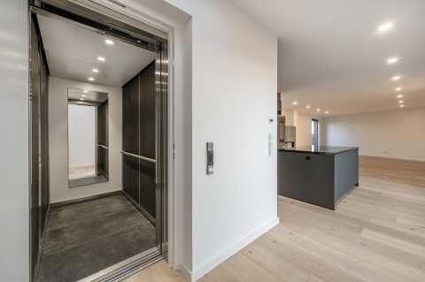 Moderner Aufzug in heller Wohnung mit Küche und offenem Wohnraum.